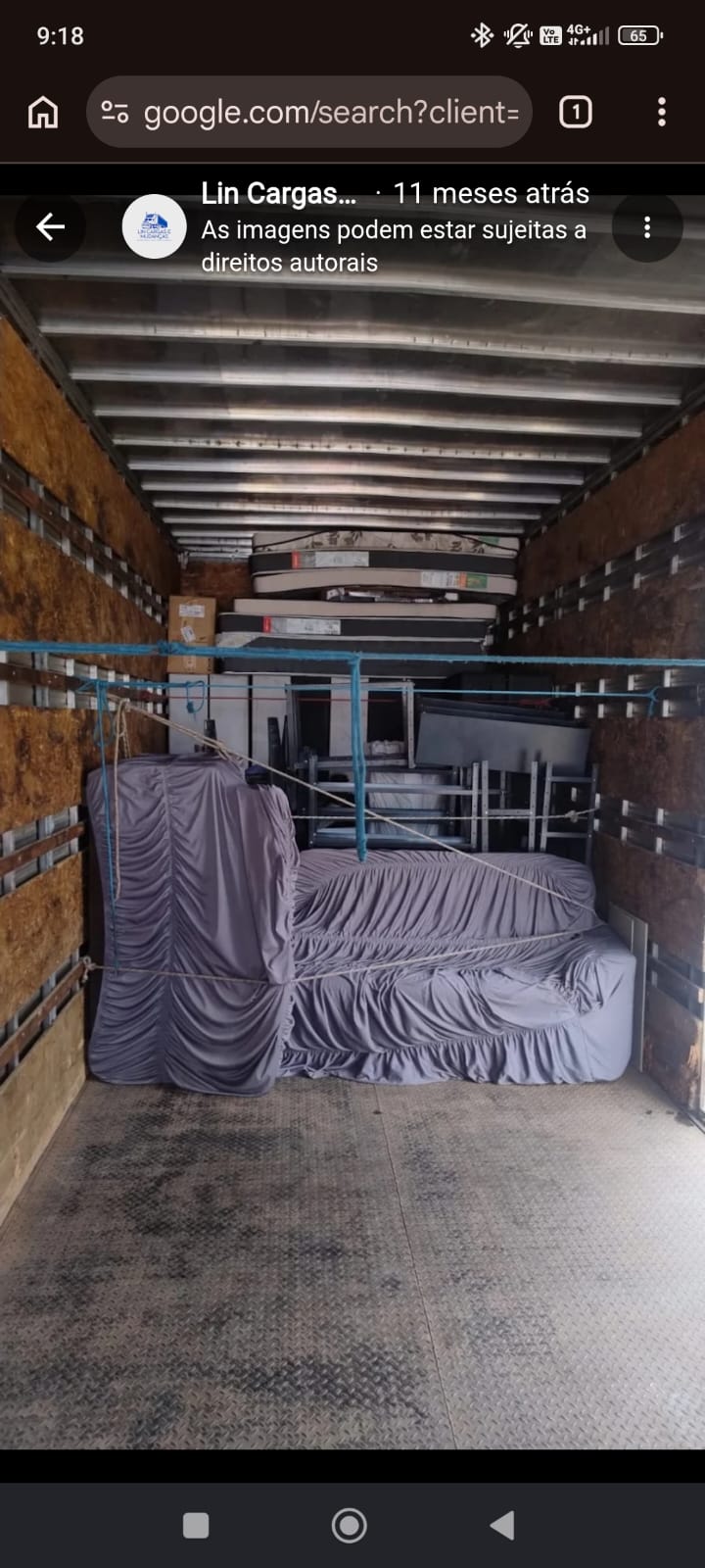 Interior do baú com sofá e guarda-roupa cobertos por capa cinza, amarrados com corda azul, e colchões ao fundo